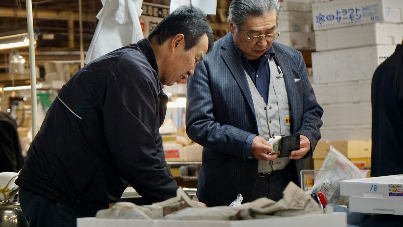 倉庫の棚の間を歩きながら打ち合わせをするスタッフ